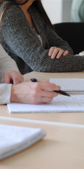 Gruppe von Schülern, die Notizen in einem gut beleuchteten Klassenzimmer während eines Meetings schreiben.